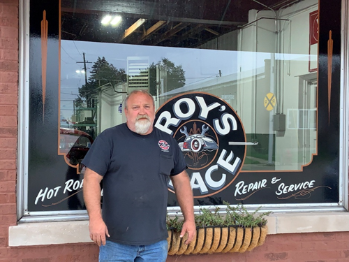 Roy standing if front of his shop